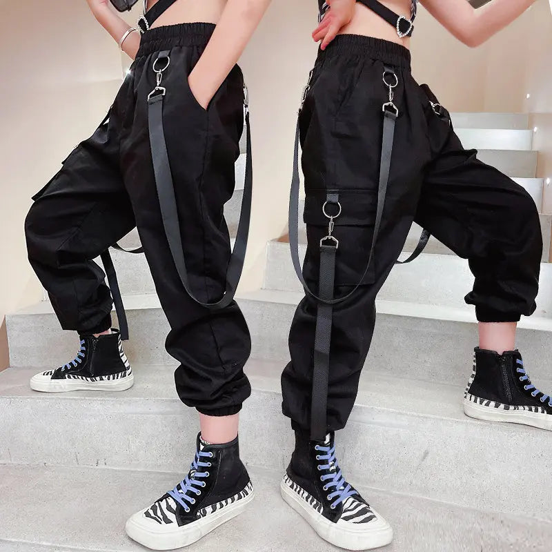 Two people wearing black suspenders and high-top sneakers on a neutral background