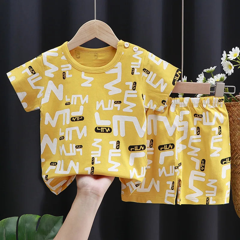 Yellow children's outfit with white patterns on a hanger against a dark background.