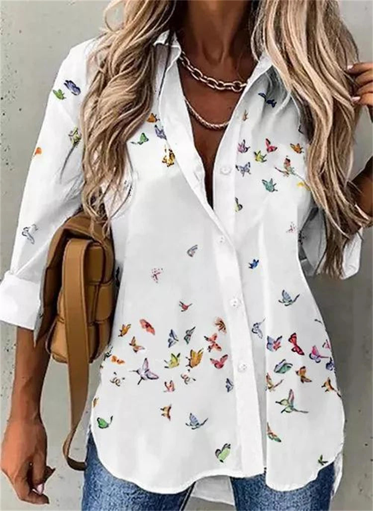 White shirt with colorful butterfly pattern worn by a person, holding a brown bag.