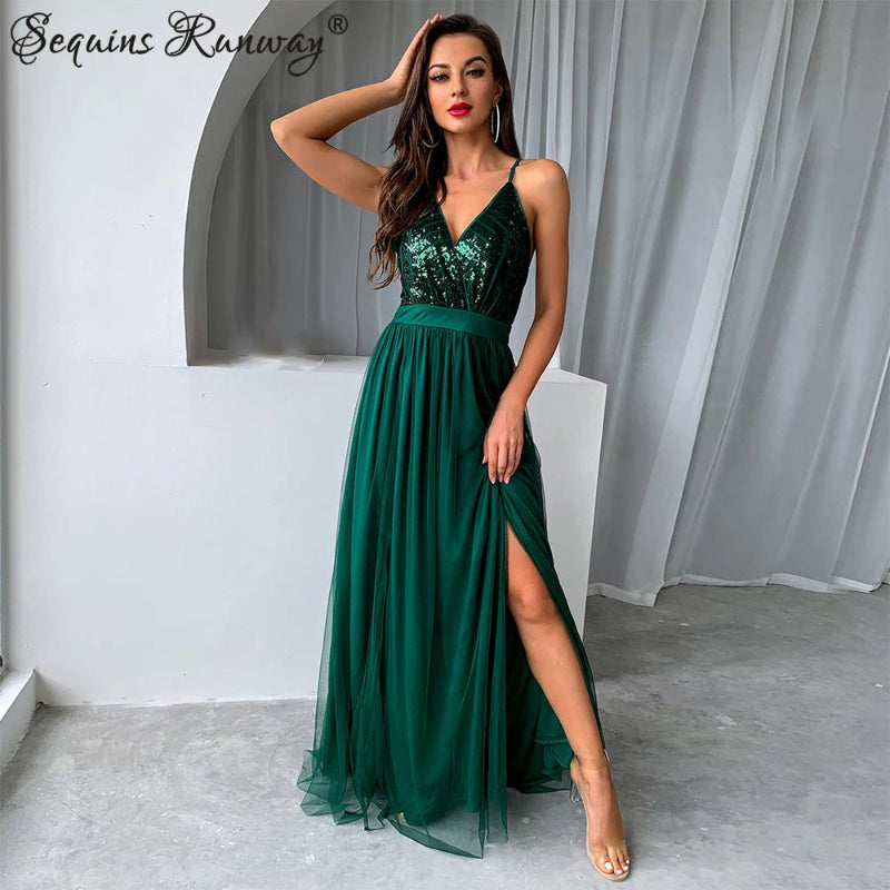 Woman wearing a green sequin dress with a slit, posing in a minimalistic setting.
