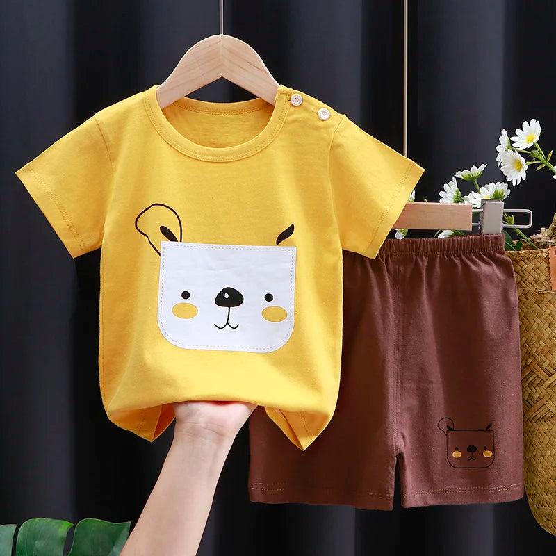 Yellow t-shirt with bear face design and brown shorts with bear face on a hanger against a dark background.
