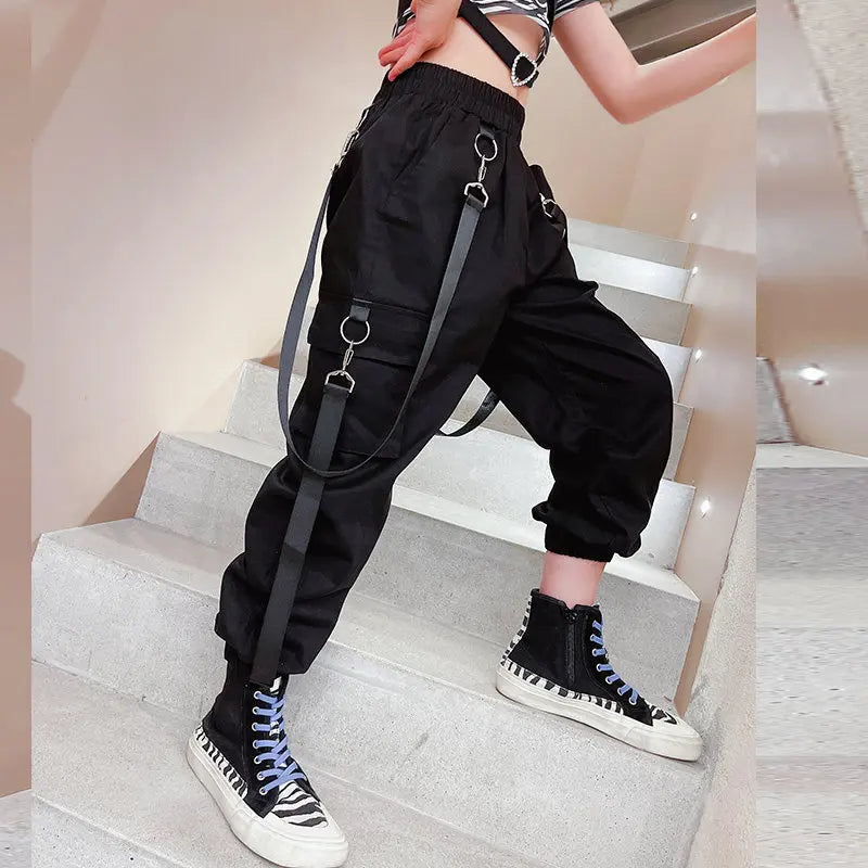 Person wearing black suspenders and high-top sneakers on a staircase.