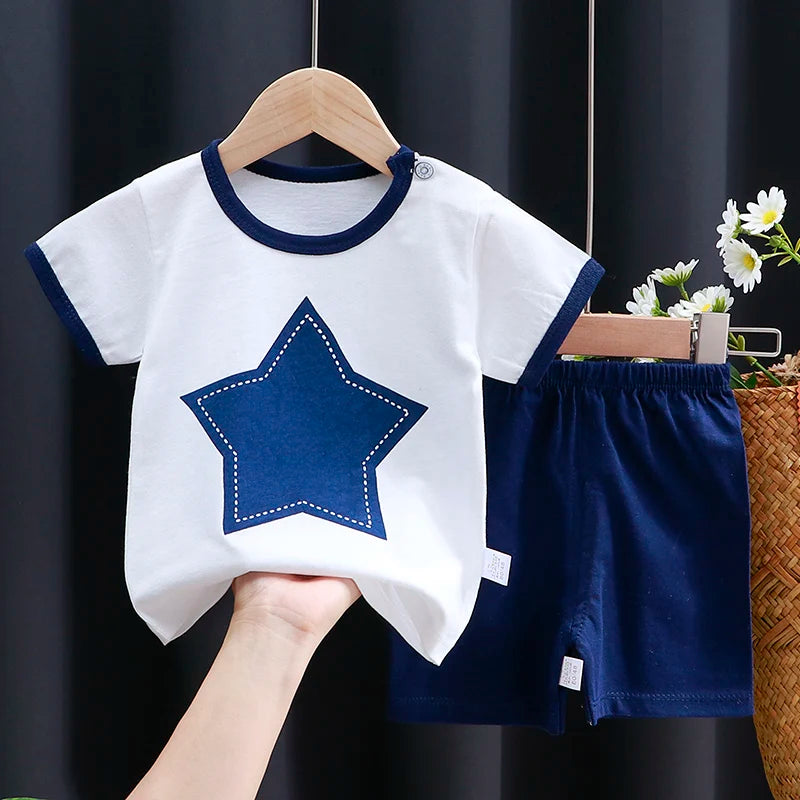 Children's white t-shirt with blue star design and matching shorts on a hanger against a dark background.