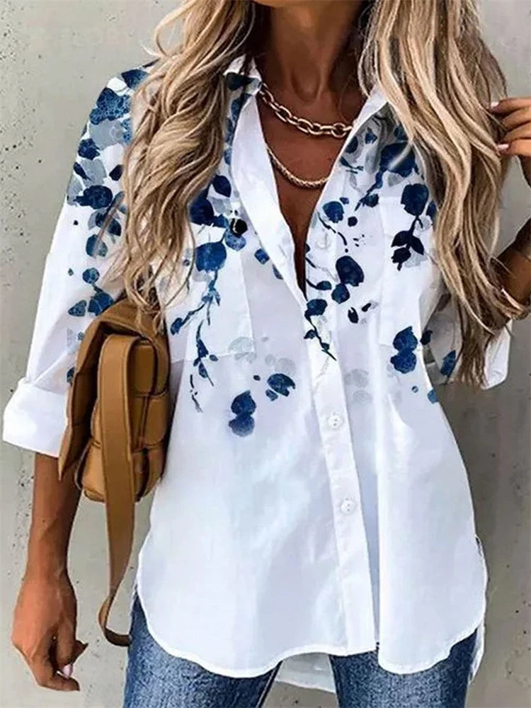 Woman wearing a white shirt with blue floral pattern and carrying a brown bag.