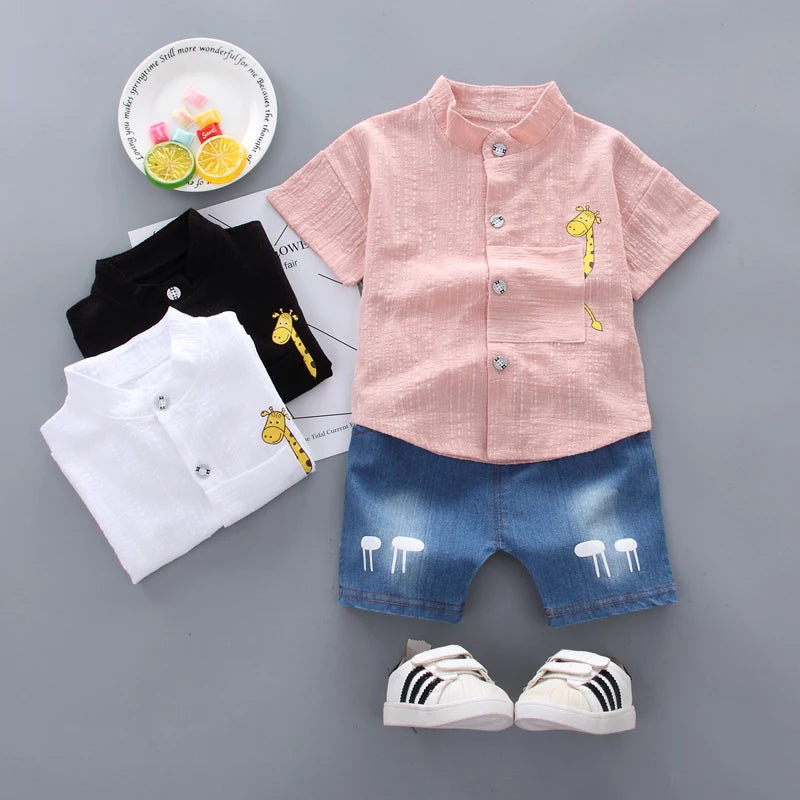 Children's clothing set with pink shirt, black and white pants, blue shorts, and white sneakers on a gray background.