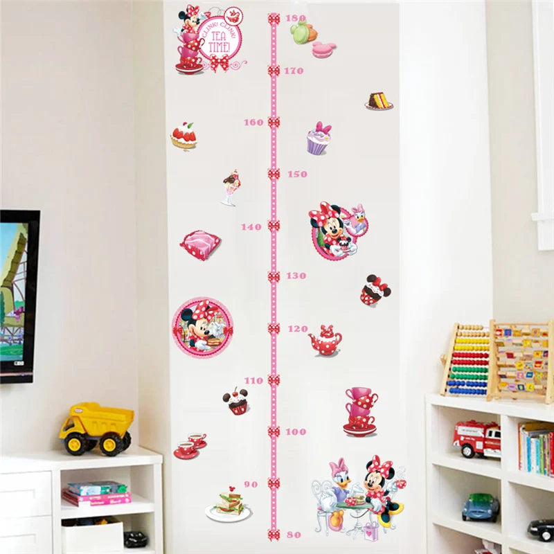 Minnie Mouse-themed height chart on a wall with toys and books below.