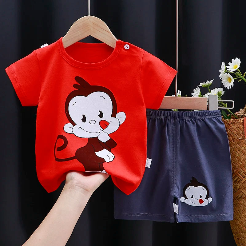 Smiling toddler wearing a cartoon-print cotton T-shirt and matching shorts, playing outdoors in sunny weather