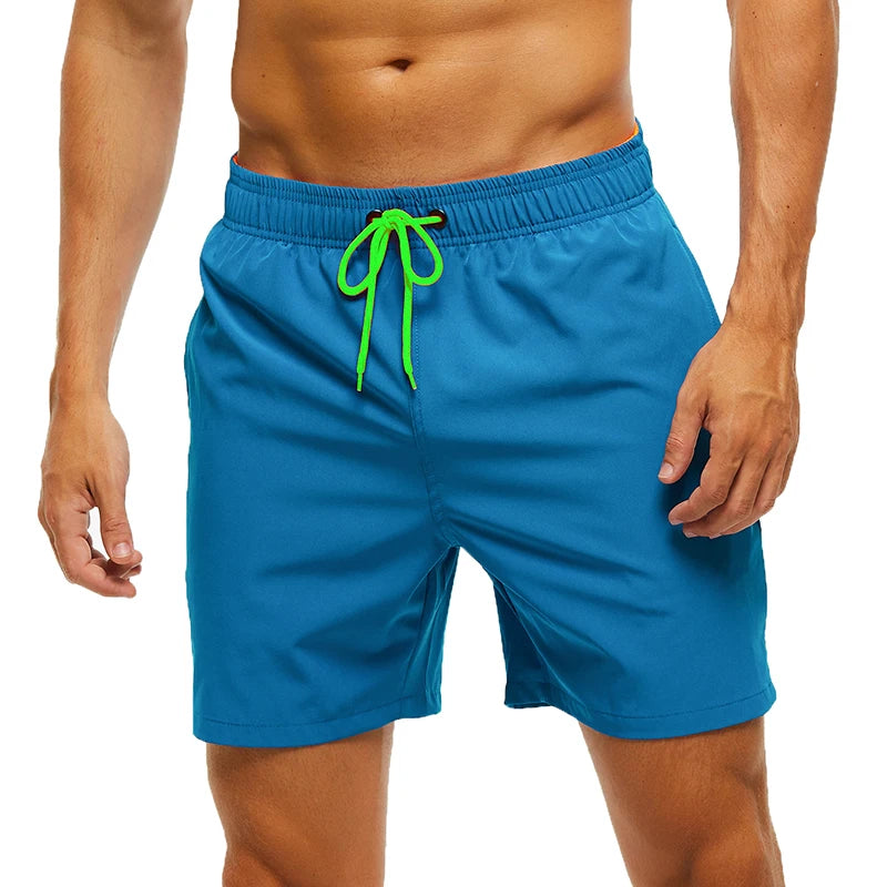 Blue swim shorts with a green drawstring on a white background