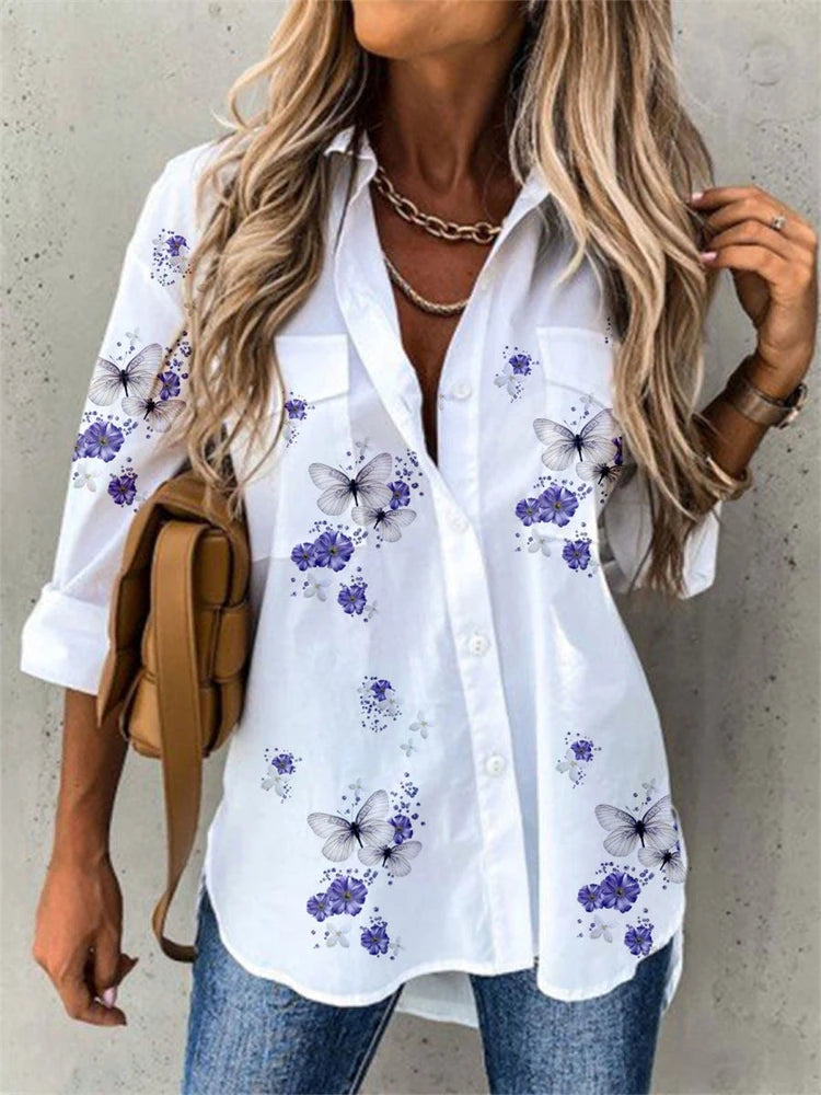 Woman wearing a white shirt with butterfly and flower patterns against a concrete wall.