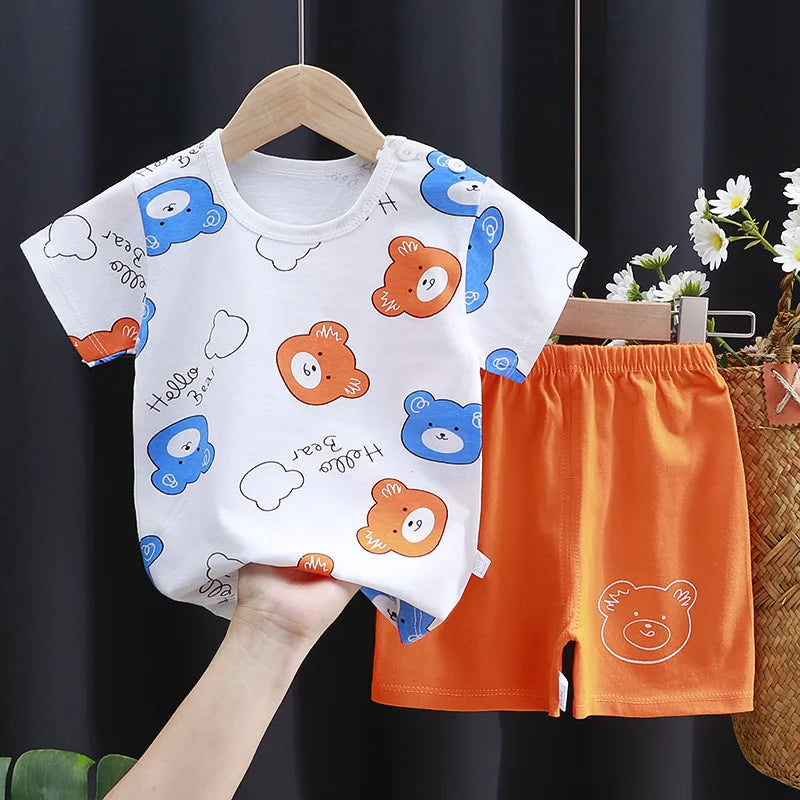 Children's outfit with a white shirt and orange shorts featuring bear illustrations, held against a dark background.