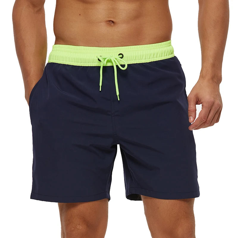 Navy swim shorts with a bright green waistband on a white background