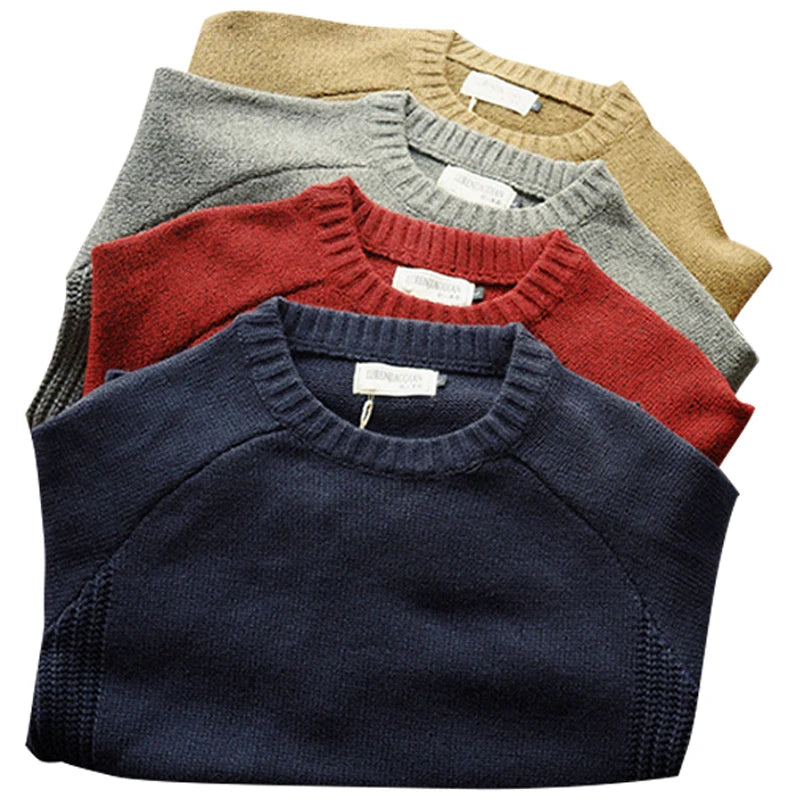 Stack of folded sweaters in navy, red, gray, and beige on a white background