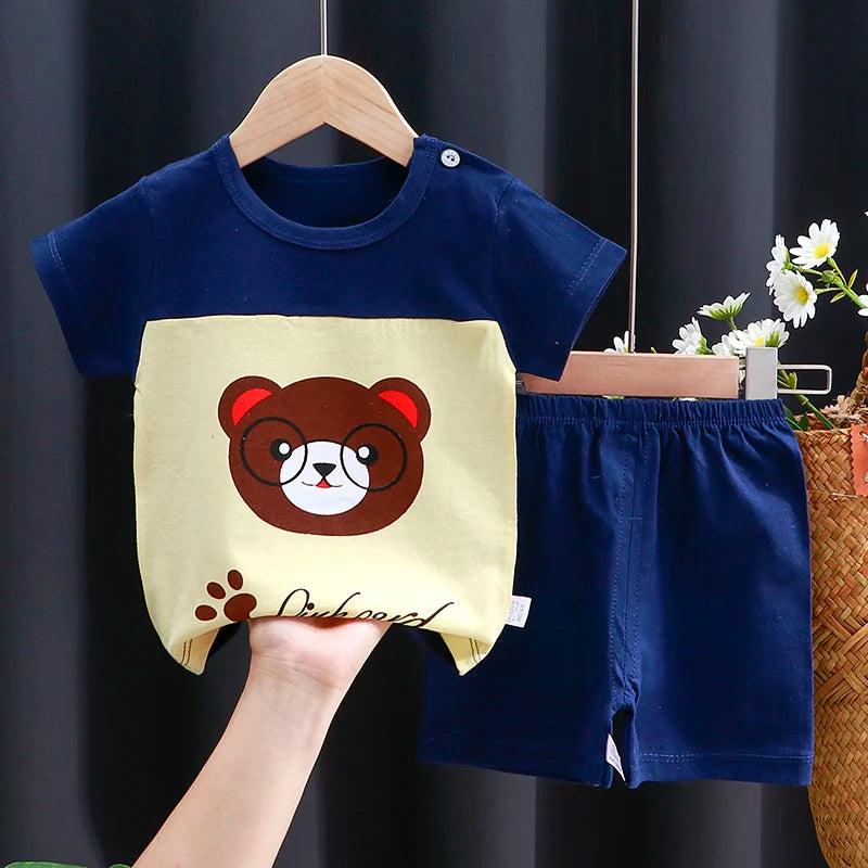 Children's navy blue shirt with bear design and shorts on a hanger against a dark background.