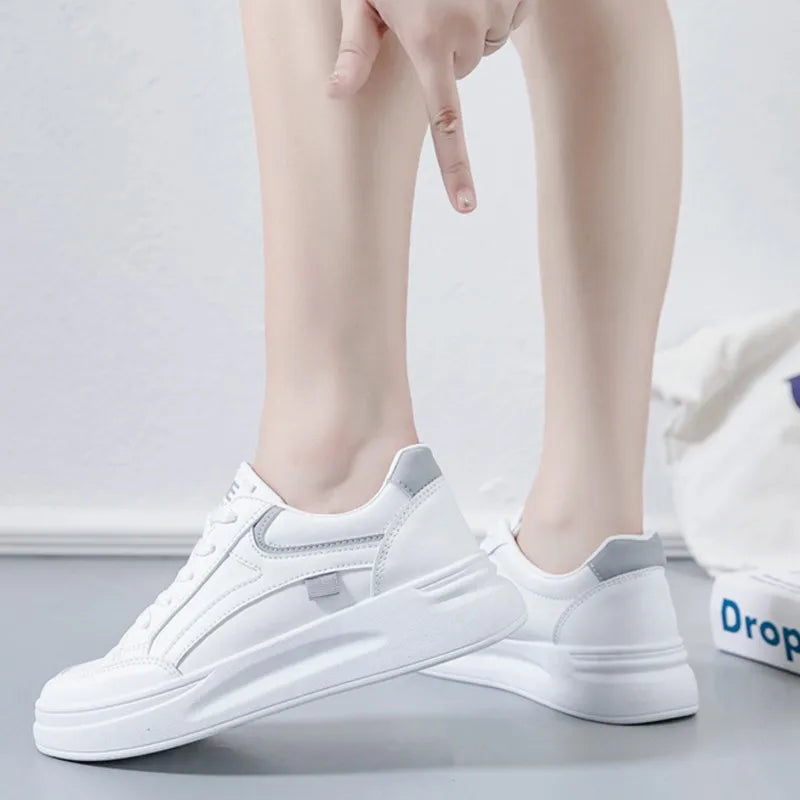 White sneakers worn by a person on a light gray background
