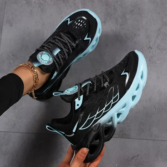 Black and blue sneakers being held up against a gray background