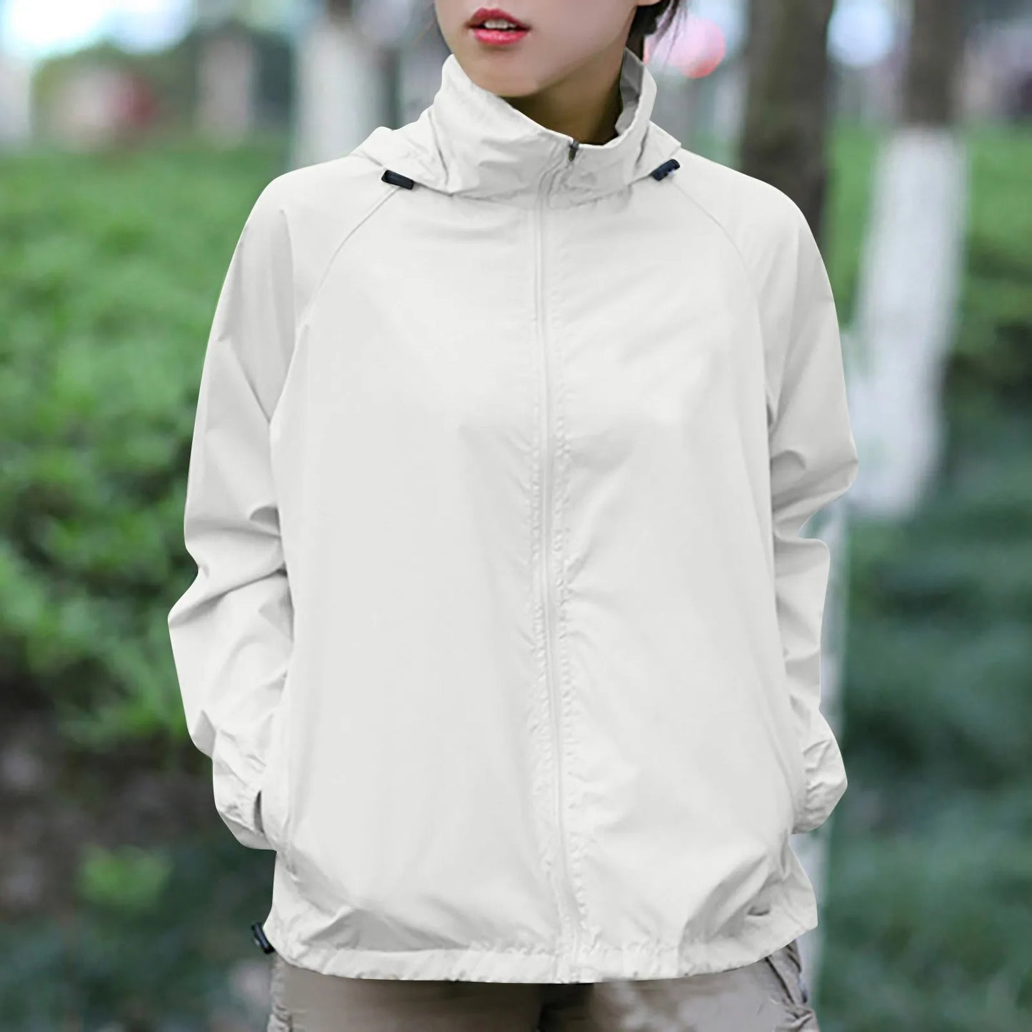 Person wearing a light gray jacket in an outdoor setting with blurred greenery