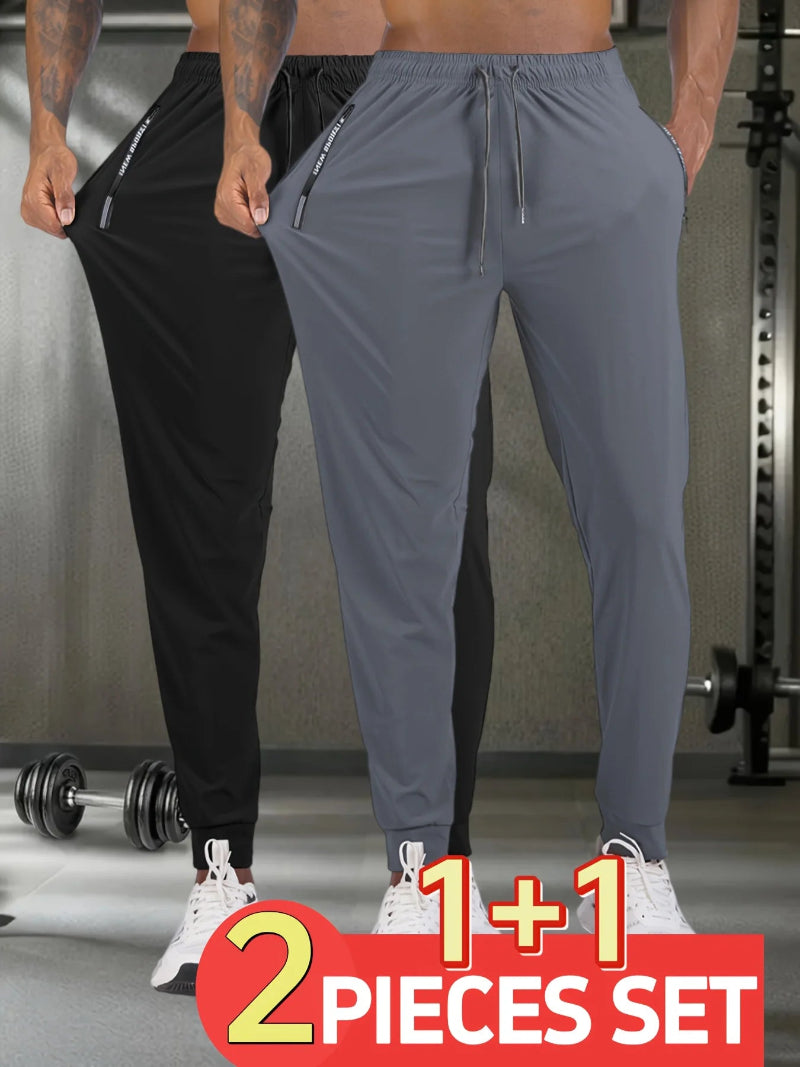 Two pairs of jogger pants, one black and one gray, worn by a person in a gym setting with a promotional banner.