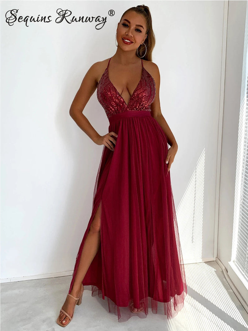 Woman wearing a burgundy evening gown with lace top and sheer sides, standing indoors.