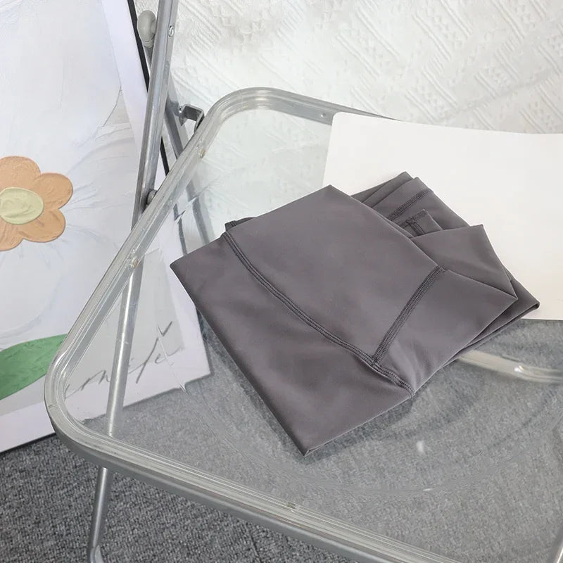 Gray folded fabric on a glass table with a white wall and floral decoration in the background
