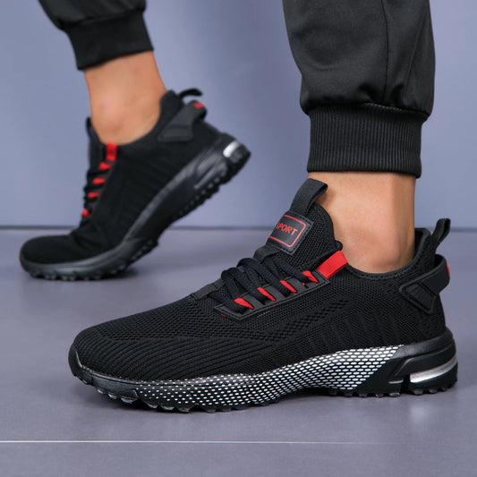 Black and red athletic shoes worn by a person on a gray background