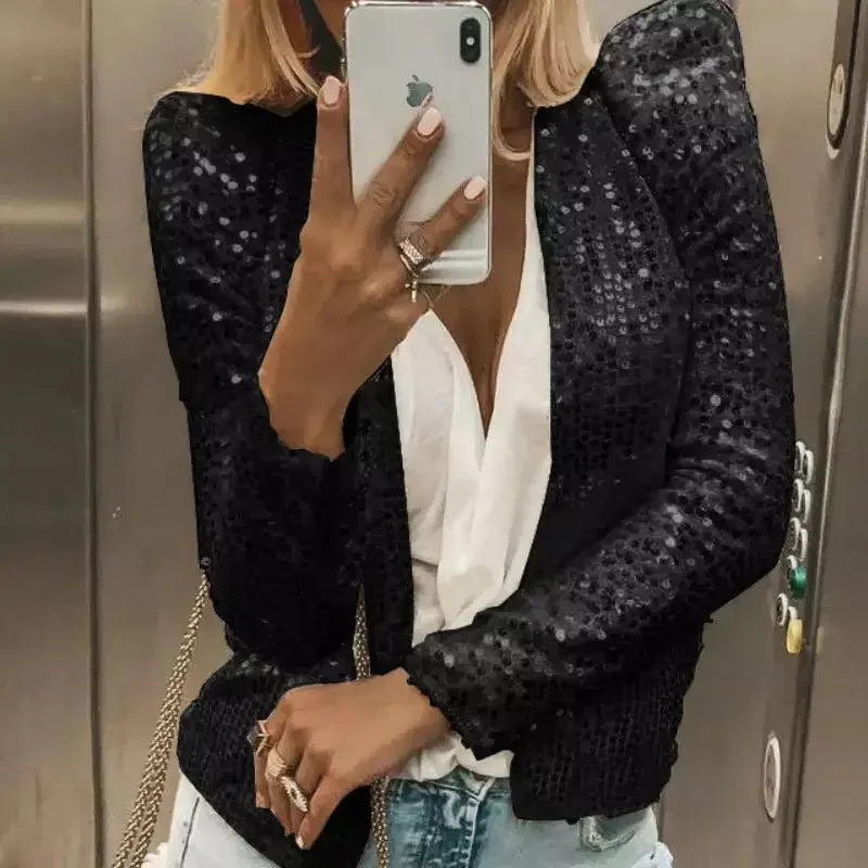 Person wearing a black sequin jacket taking a mirror selfie.