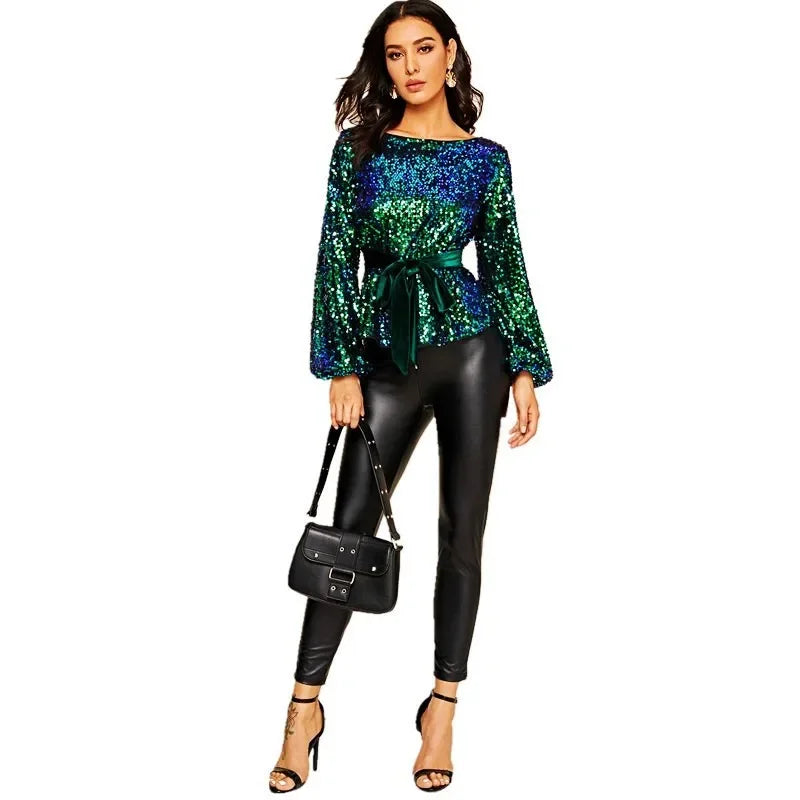 Woman wearing a green sequin top and black leather pants on a white background