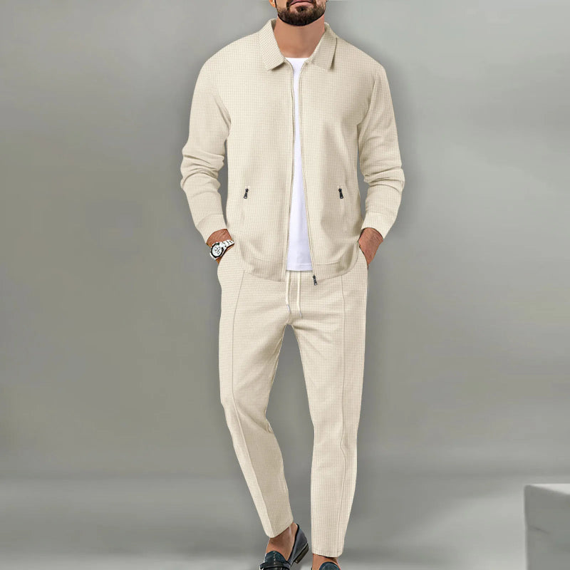 Man wearing a beige tracksuit against a gray background