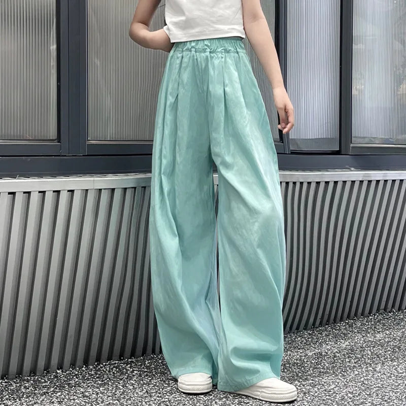Person wearing light blue pants and white shoes standing against a metallic wall.