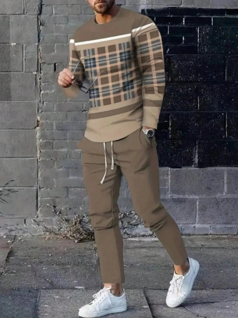 Man wearing a plaid sweater and brown pants against a brick wall.