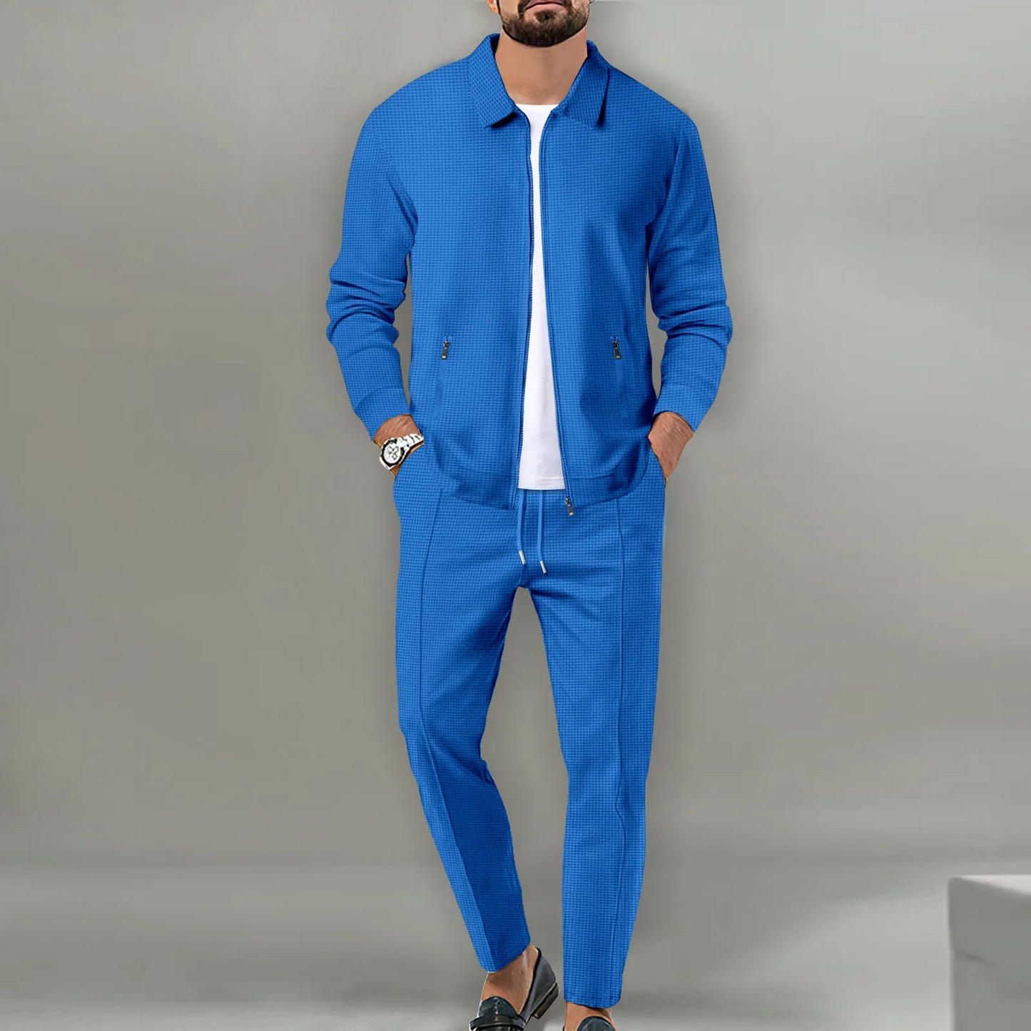 Man wearing a blue tracksuit against a gray background