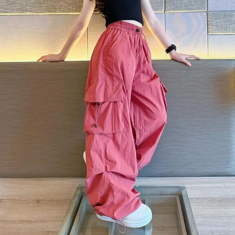 Person wearing red cargo pants and white sneakers standing on a glass platform.