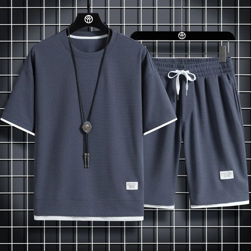 Gray t-shirt and shorts set with a necklace on hangers against a grid background