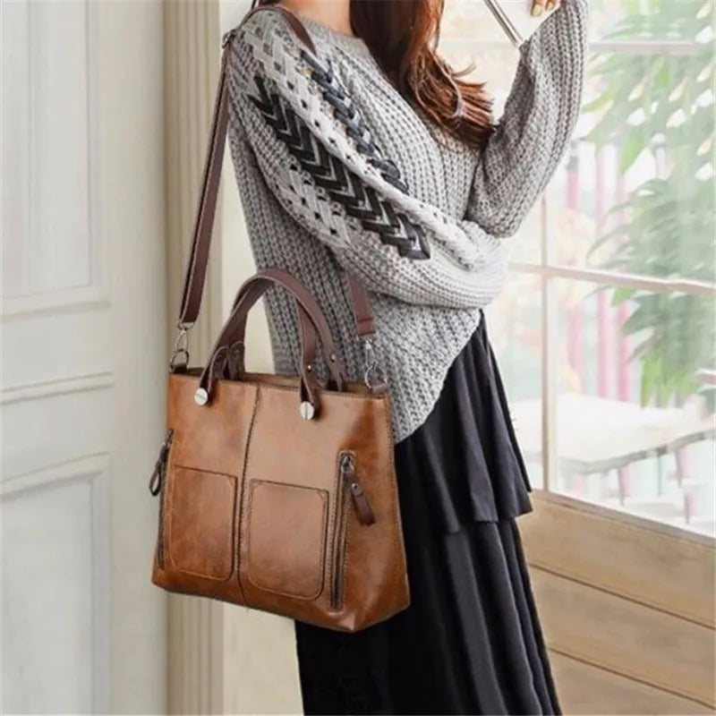 Person holding a brown leather handbag indoors