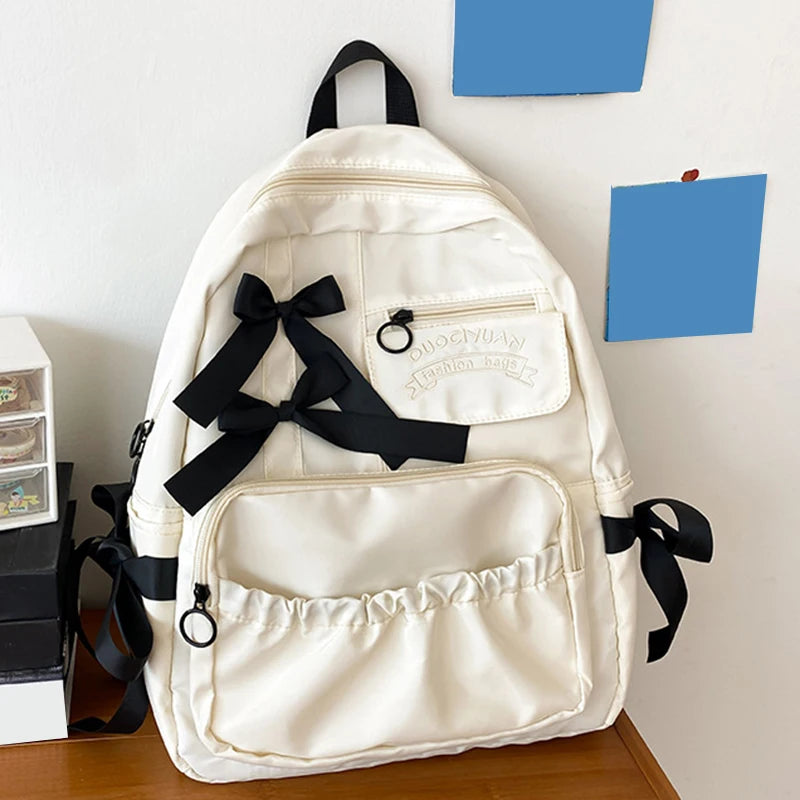 White backpack with black ribbons on a wooden surface