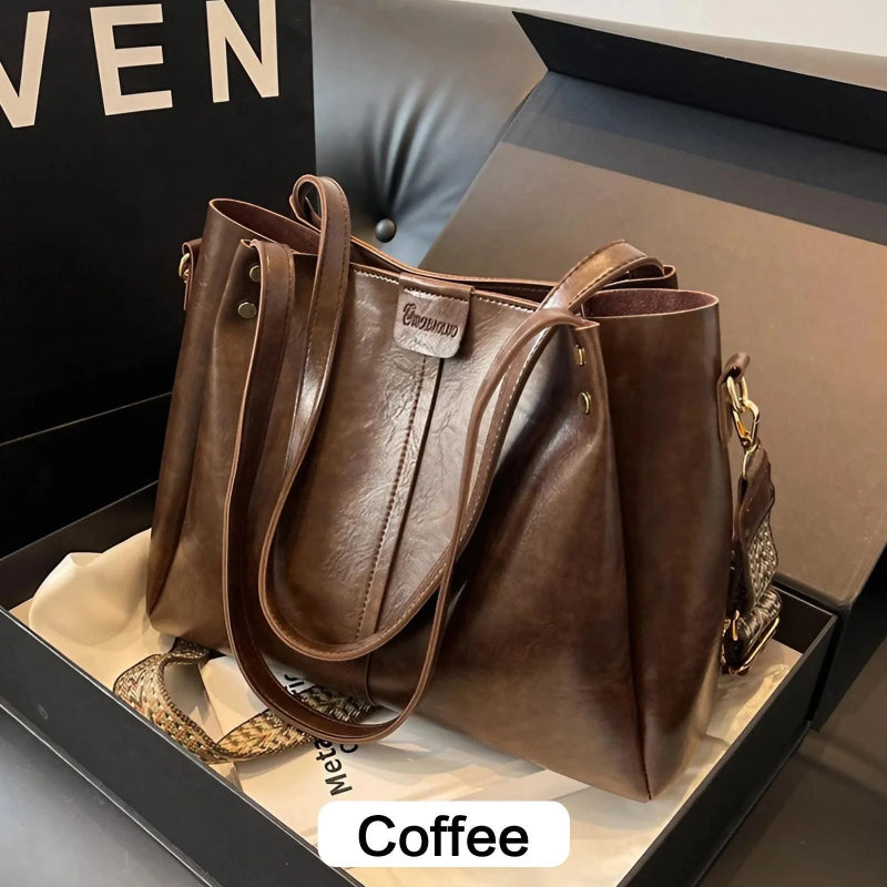 Brown leather handbag with a visible brand logo on a dark surface.