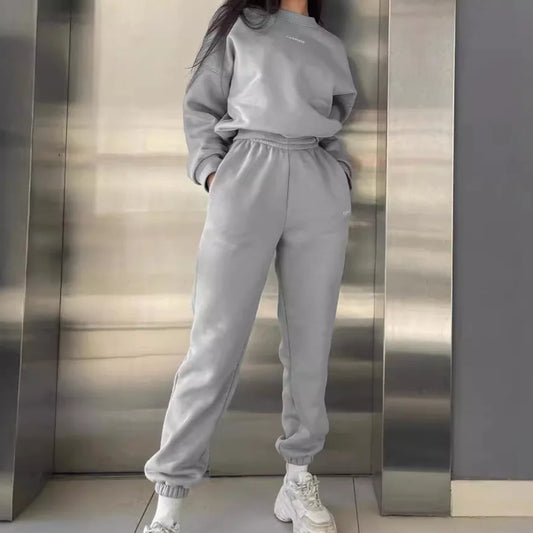 Person wearing a gray tracksuit standing in front of a metallic wall.