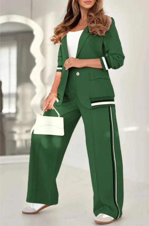 Woman wearing a green suit with white accents, holding a white handbag indoors.