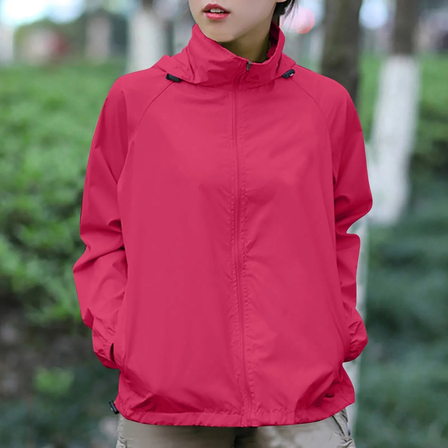 Person wearing a red jacket outdoors with greenery in the background