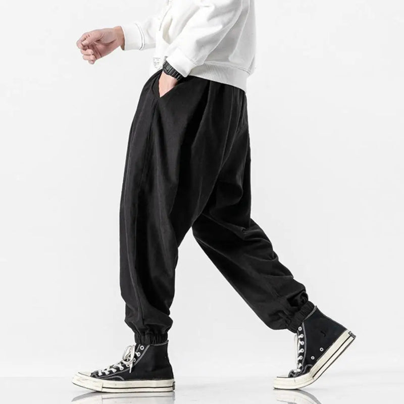 Person wearing black baggy pants and black sneakers on a white background