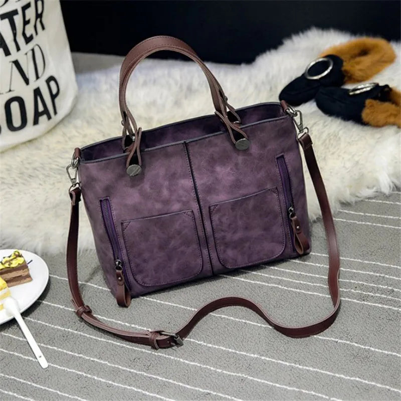 Purple handbag with brown straps on a gray surface
