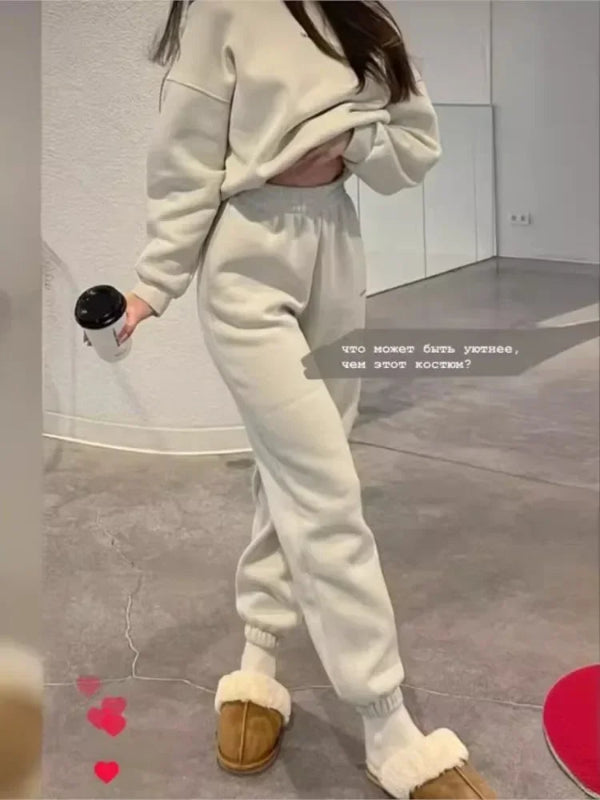 Person wearing a white tracksuit with brown slippers in a room.