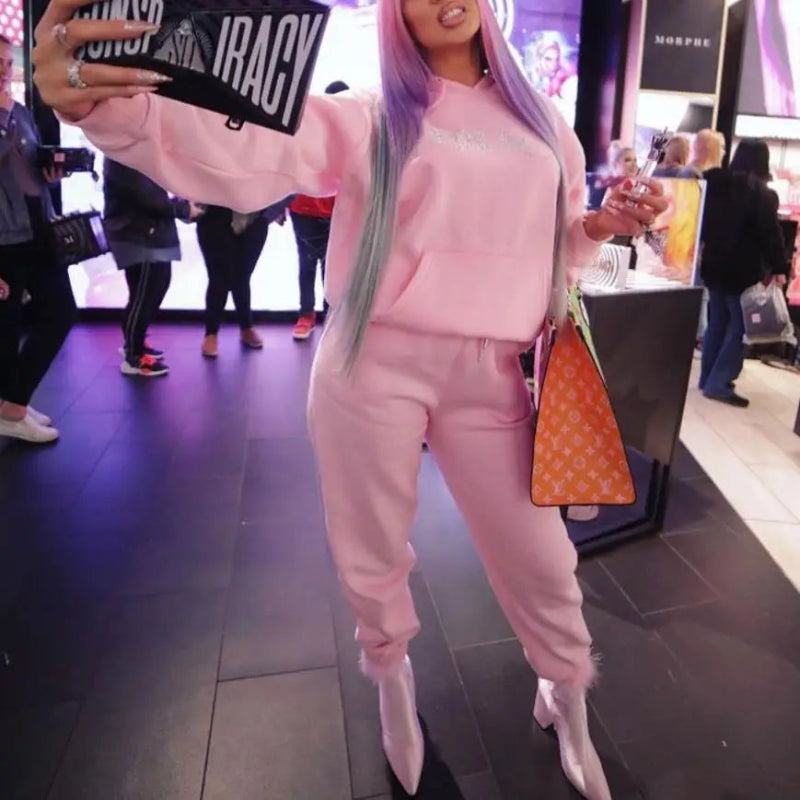 Person in pink outfit taking a selfie in a store with visible branding.
