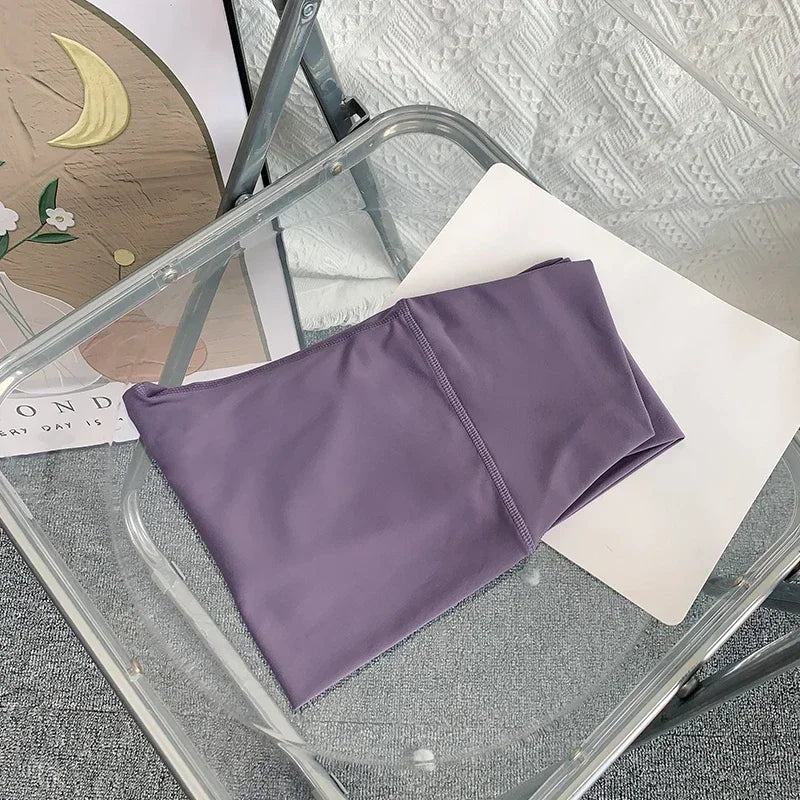 Purple garment on a glass table with a textured wall and decorative items in the background