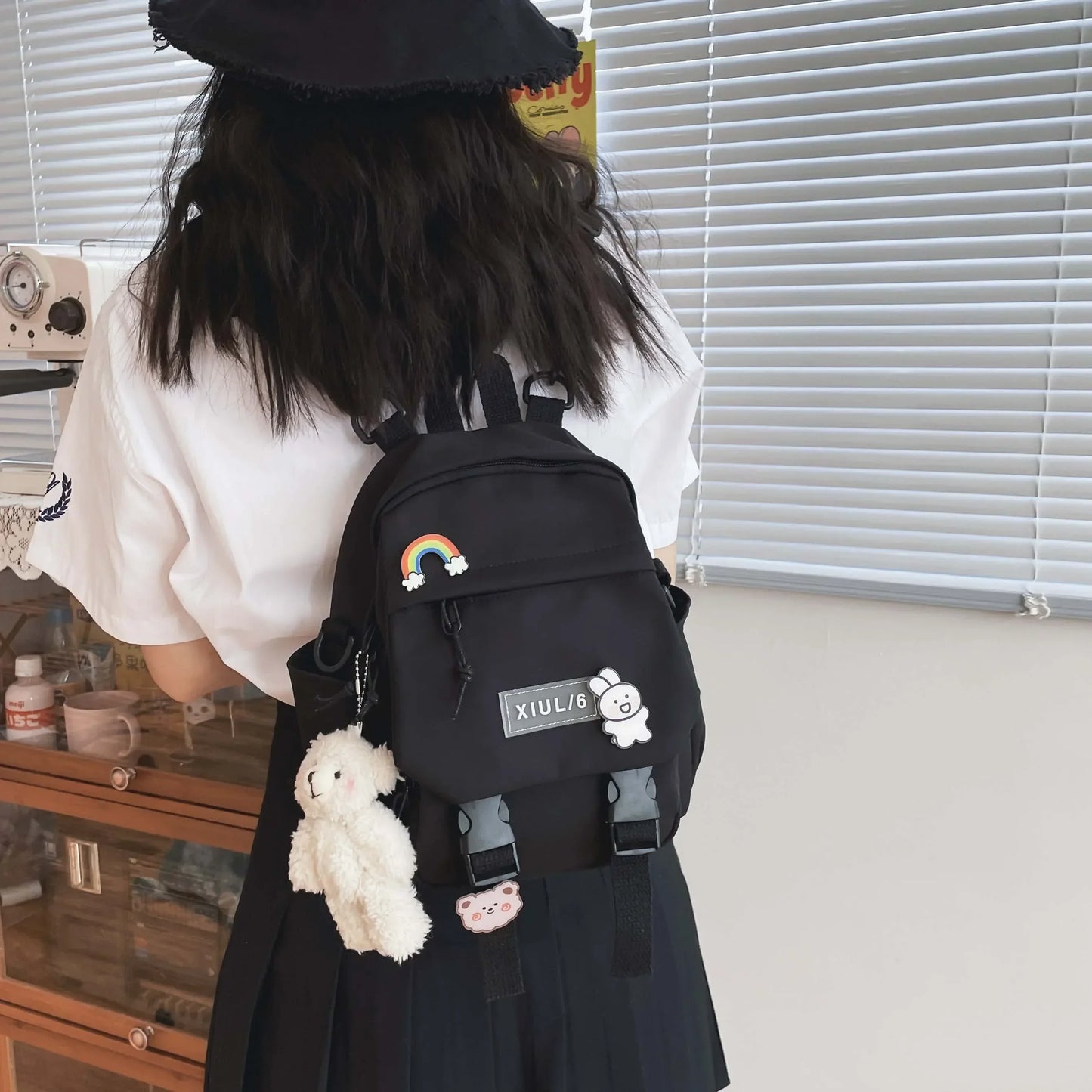 Person wearing a black backpack with rainbow design and 'XIUL' label indoors.
