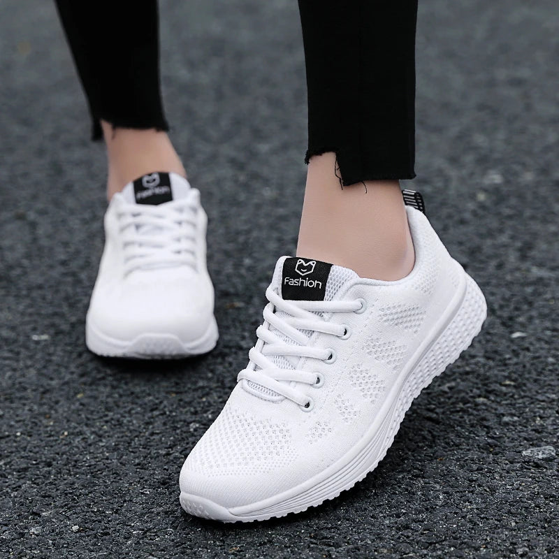 White sneakers with black labels on a gray pavement background