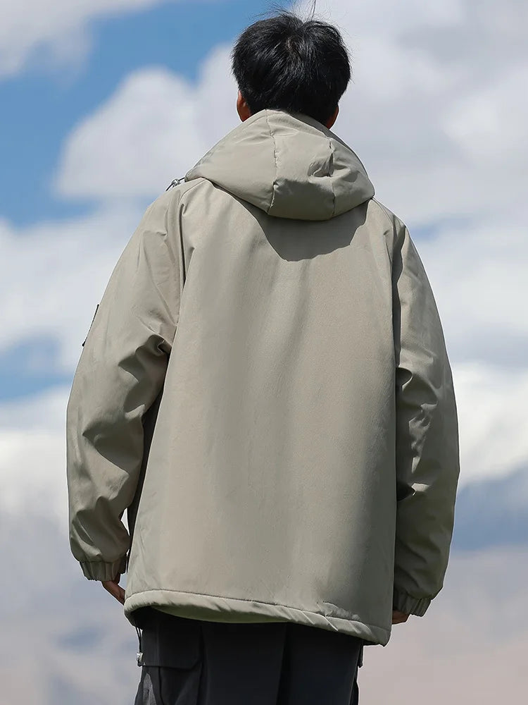 Person wearing a beige jacket against a blue sky with clouds