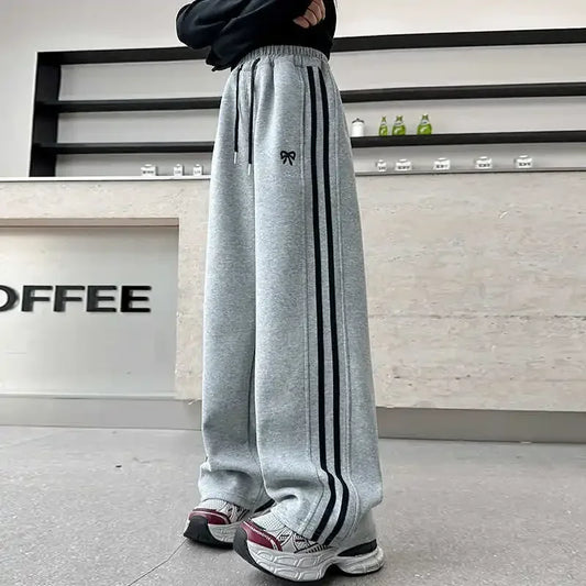 Person wearing gray sweatpants with black stripes in a coffee shop setting