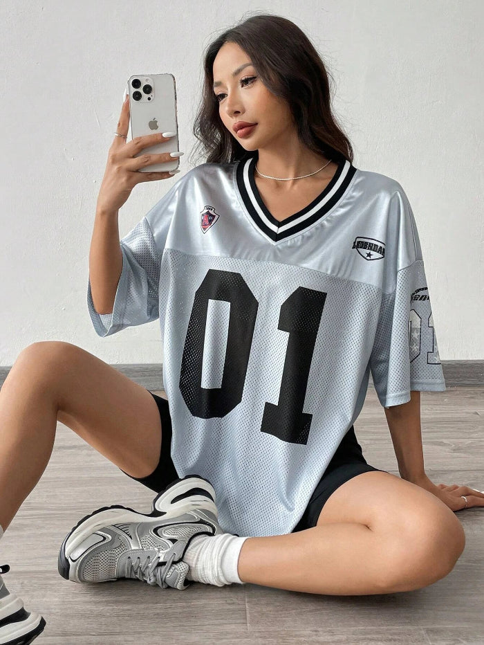 A woman wearing a black V-neck sports jersey with the number '01' on it. The jersey has white text and trim, and it appears to be made of polyester fabric.