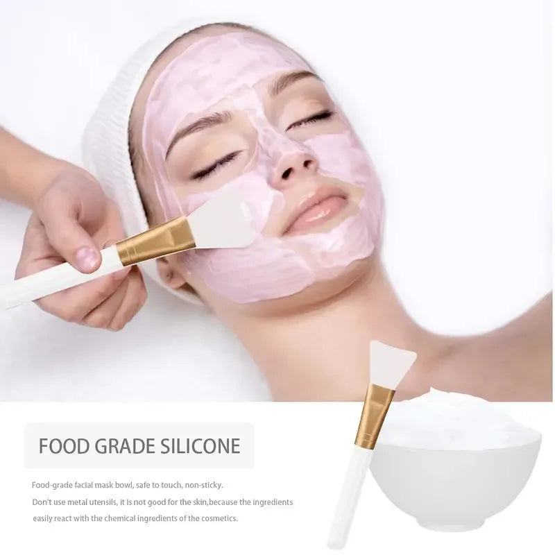 Person applying a pink facial mask with a brush on a white background