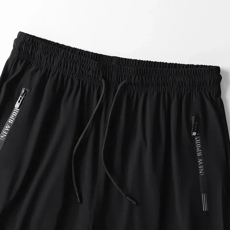 Black athletic shorts with drawstring and side zippers on a light gray background